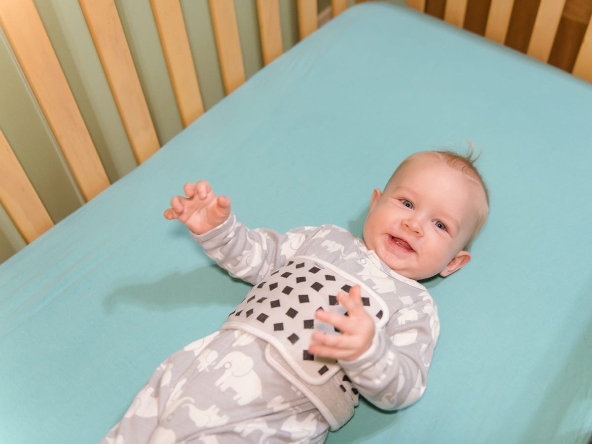 a baby in a crib wearing the nanit plus band used for tracking movement