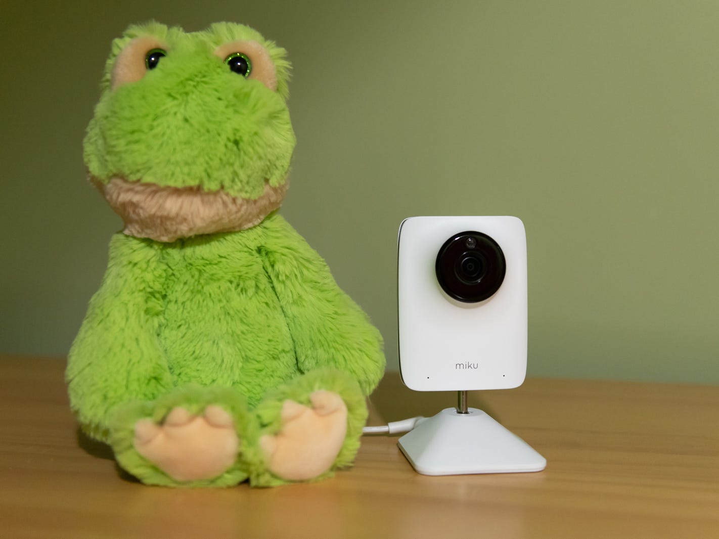 miku smart baby monitor on a dresser beside a green stuffed frog toy