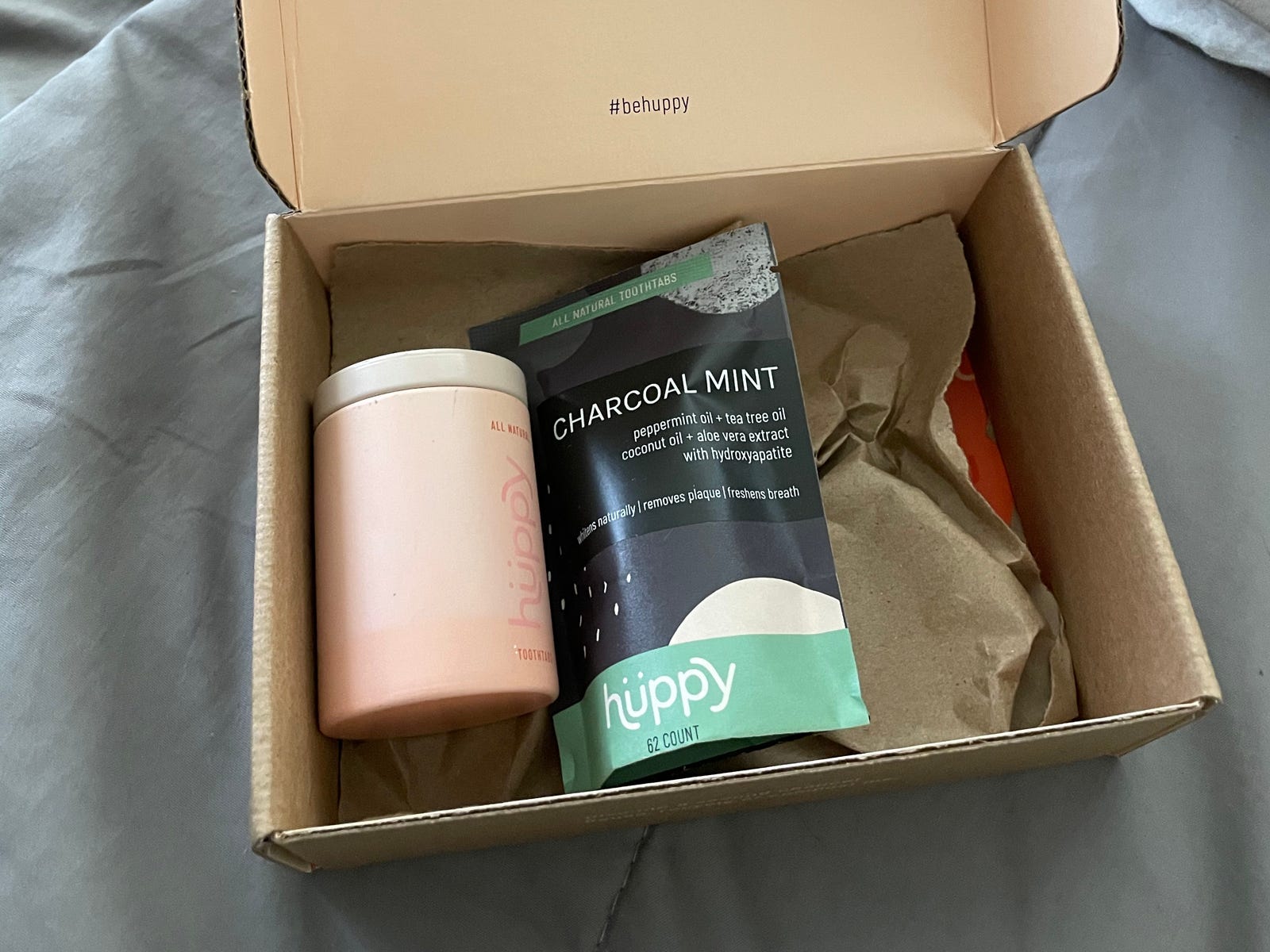an open box of toothpaste products sitting on a bed