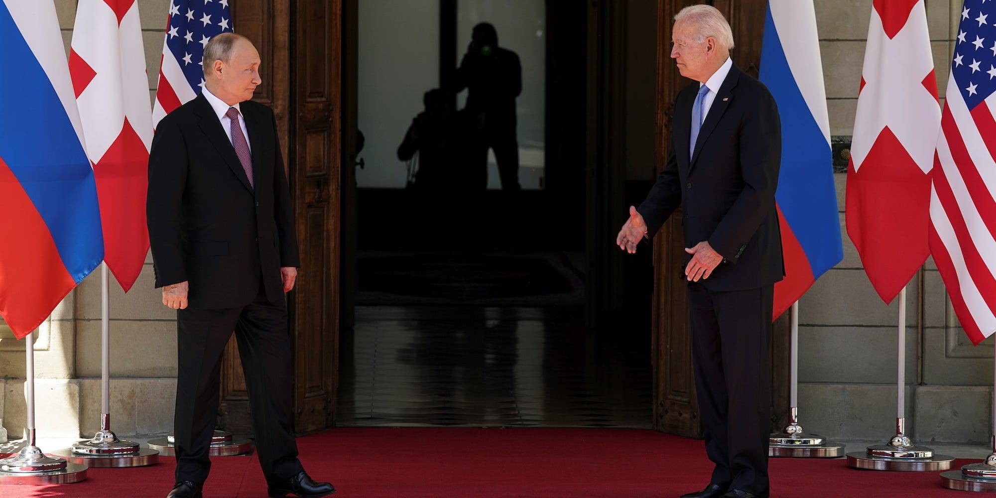 Presidents Vladimir Putin and Joe Biden facing each other at the doorway to the building where they are to meet