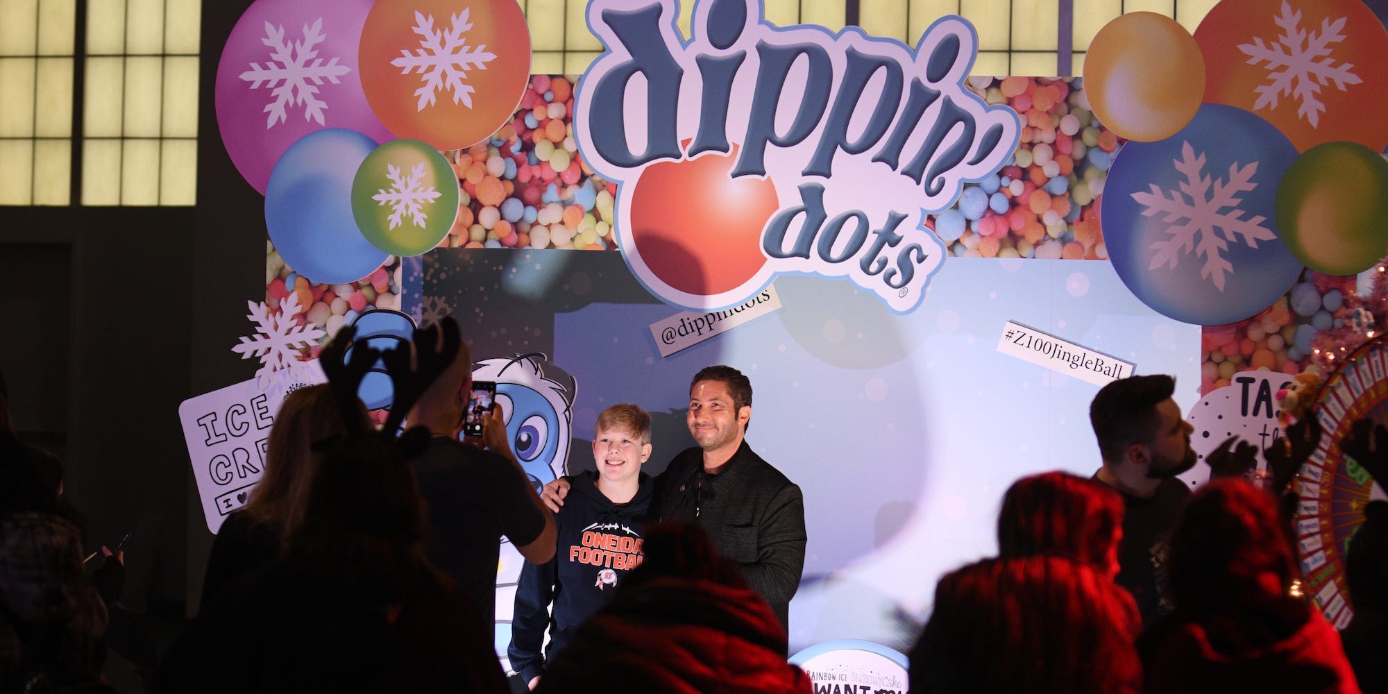 Dippin' Dots CEO Scott Fischer poses with fans at a 2019 event in front of the company logo