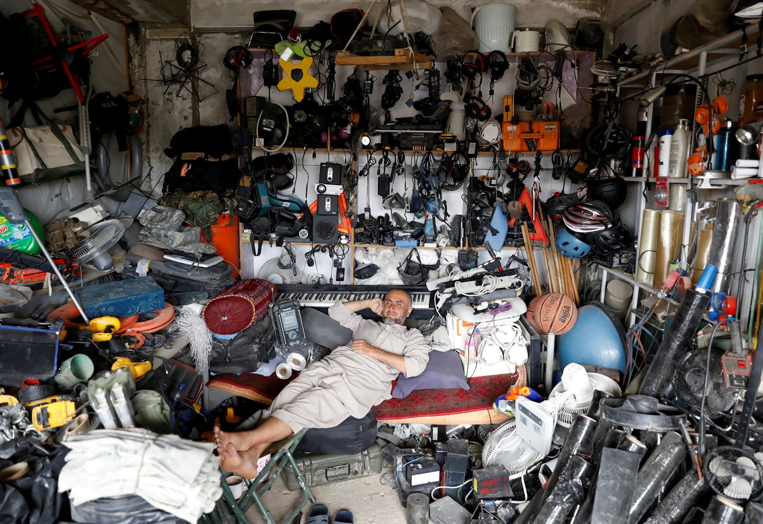 An Afghan man rests in his shop as he sell US secondhand materials outside Bagram air base, after American troops vacated it.